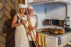 Dwie kobiety stoją przy starym piecu w kurpiowskiej chacie