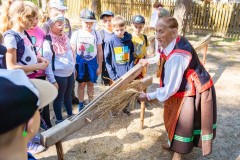 Kobieta w kurpiowskim stroju demonstruje obróbkę lnu