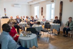 Publiczność siedząca przy okrągłych stolikach.