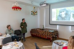 Podróżniczka stojąc przed publicznością opowiada o wyprawie. Z prawej strony fragment ekranu z wyświetloną prezentacją.
