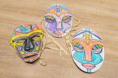 Trzy kolorowe maski z papieru leżąca na stole.