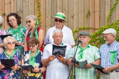 Chórzyści, kilka osób, stoją na scenie i śpiewają w tężni solankowej