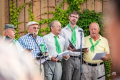 Pięciu chórzystów śpiewa stojąc na scenie