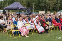 Uczestnicy uroczystości siedzą na widowni w plenerze
