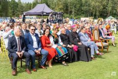 Wielu ludzi, uczestników wydarzenia w plenerze siedzących na krzesłach
