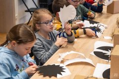 Dzieci siedząc przy stole wycinają kształty z papieru