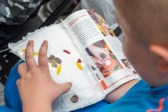 Dziecko trzyma na kolanach folder oraz zdobioną kartkę z papieru czerpanego