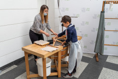 Chłopczyk z pomocą instruktorki czerpie papier