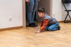 Chłopiec klęcząc na terakocie gra w kapsle