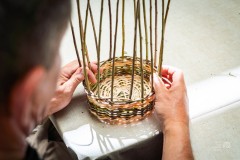 Dłonie wyplatające naczynie z wikliny