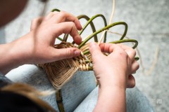 Dłonie wyplatające koszyk z wikliny