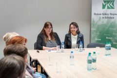 Prelegentka oraz tłumaczka siedzące przy stole, z lewej strony goście spotkania