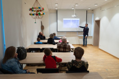 Grupa ludzi słucha wykładu oraz ogląda wyświetlone zdjęcia.