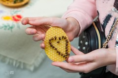 kobieta pokazuję ozdobę zrobioną z plastra wosku z wbitymi w niego goździkami 