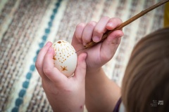 Dłonie dziecka wykonujące pisankę metodą batikową