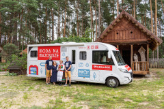 Czwórka ludzi na tle kampera w skansenie.