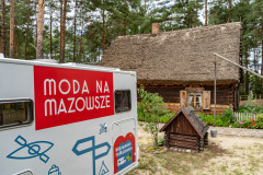 Kamper w skansenie, w tle widać domek oraz ogródek.