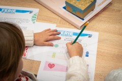 Dłonie dziecka piszące na karcie edukacyjnej