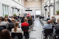 Uczestnicy podczas konferencji. W tle, z mównicą stoją prowadzący konferencję