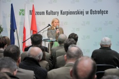 Kobieta przy mikrofonie przed widownią w tle napis MKK