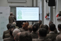 Mężczyzna z mikrofonem opowiada treść na projektorze przed widownią 