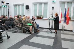 Kobieta stoi przy mikrofonie przed widownią w dziedzińcu muzealnym 