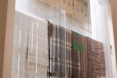 Duża, oszklona gablota na wystawie, w której prezentowane są tkaniny i plecione kosze
