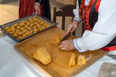 Dłonie krojące ciasto na  fafernuchy. Dalej blacha z fafernuchami