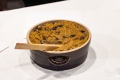 Na stole bigos w glinianym naczyniu z wetkniętą drewnianą łyżką