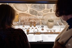 Dwie osoby przyglądają się zabytkom archeologicznym leżącym w gablocie