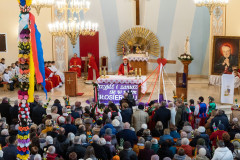 Uroczysta msza święta w Niedzielę palmową. Kościół wypełniony wiernymi. Widoczna wysoka palma. Widok z chóru w kierunku  ołtarza. Z prawej strony widoczny obraz kardynała Stefana Wyszyńskiego.