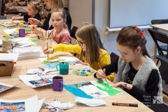 Dzieci siedzące przy stole i malujące obrazki w stylu Tingatinka