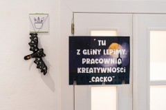 Nietoperz-zabawka oraz tablica z napisem „Tu z gliny lepimy. Pracownia kreatywności »Cacko«”