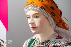 Manekin w chuście pomarańczowej w stroju kurpi białych