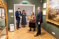cztery osoby stoją, jedna z nich trzyma obraz