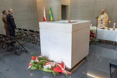 Sarkofag, w którym spoczywają prochy żołnierzy poległych w bitwie pod Ostrołęką. W tle ksiądz odprawiający mszę świętą w krypcie. Z lewej strony stoją uczestnicy uroczystości.