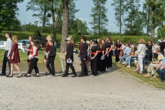 Na terenie Fortów Bema młodzież, członkowie chóru w odświętnych strojach idzie w parach na scenę. Z prawej goście na widowni.