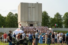 Chór występujący na schodach Pomnika Mauzoleum. Na trawie replika armaty, wokół stoją goście wydarzenia.