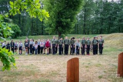 Ponad trzydziestu harcerzy i harcerek stoi w dwuszeregu na terenie Fortów Bema. W tle niewielkie wzniesienie i drzewa