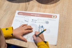 Dłonie dziecka rozwiązującego kartę edukacyjną