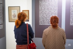Dwie kobiety czytają treści na planszy wystawowej