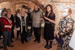 Dyrekcja Muzeum, autorka wystawy oraz uczestnicy wernisażu stoją podczas otwarcia wystawy w muzealnych piwnicach.