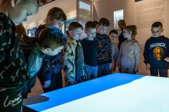 Dzieci zgromadzone wokół stołu, na którym wyświetlana jest animacja