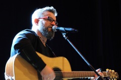 Mężczyzna przy mikrofonie grający na gitarze 