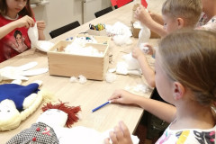 Uczestnicy twórczego spotkania wykonują szmaciane lalki