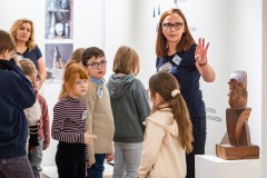 Dwie muzealniczki i kilkoro dzieci zwiedzają wystawę