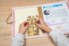 Dłonie dziecka wykonujące wklejające wycinankę do albumu