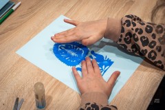 Dłonie dziecka naklejające wycinankę na kartkę papieru