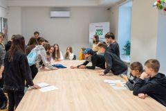 Uczestnicy lekcji historycznej rozwiązują przy stole karty edukacyjne