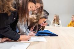 Uczestnicy lekcji historycznej rozwiązują przy stole karty edukacyjne